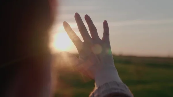 Resplandor del sol en el cielo a través de sus dedos, fantasear con la mano en una puesta de sol brillante, resplandor en el cielo, una mujer rezando al sol, viajar de vacaciones, lugar de los niños, el amor para vivir, pedir un deseo —  Fotos de Stock