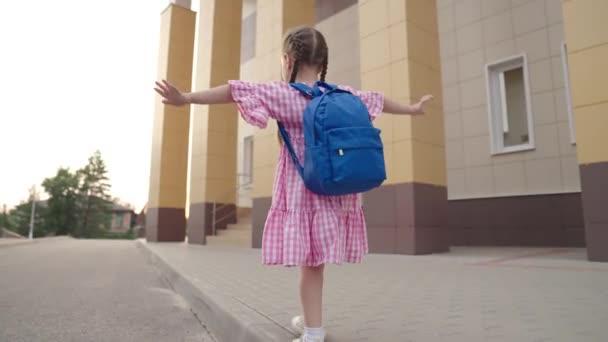 Una bambina ha alzato le mani e mantiene l'equilibrio, giochi per bambini per strada, il bambino si sta divertendo, il bambino cammina lungo il barbiere in città, intrattenimento per bambini attivo in cortile — Video Stock