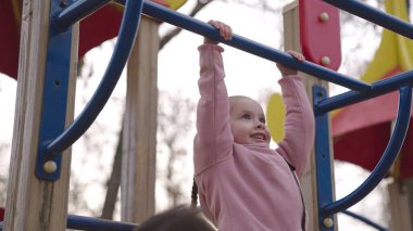 Gülümseyen küçük çocuk merdivenlerden çıkıyor, baba çocuğun oyun alanına tırmanmasına yardım ediyor, eğlenceli bir çocukluk için eğlence kompleksi, mutlu aile günü, baba günü, hafta sonu bebekle aktif istirahatte, enerjik anaokulu oyunu