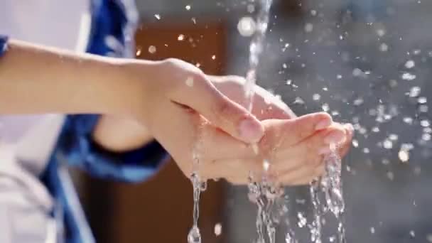 Ein Mann mit weißer Haut wäscht sich im Sommer die Hände mit Wasser in Nahaufnahme, Hauthygiene und Schutz vor Coronavirus, wäscht sich die Finger, stoppt die Ausbreitung von Bakterien, Spritzer und Tropfen fliegen Bokeh — Stockvideo