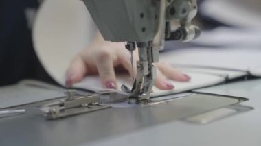 Adam dikiş makinesine kıyafet dikiyor, modern terzi modası, iğne ve iplik kumaş desenlerine dikiş dikiyor, bir üretim fabrikasında terzi, dikiş işi için ekipman dikiyor.