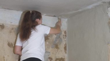 Kadın sıvacı duvarı fırçayla kaplıyor, bir apartmanın yenilenmesi, endüstriyel inşaat müteahhiti, çimento işi teknolojisi, kirli aletlerle bitiriyor, beton kaldırımla inşa ediyor.