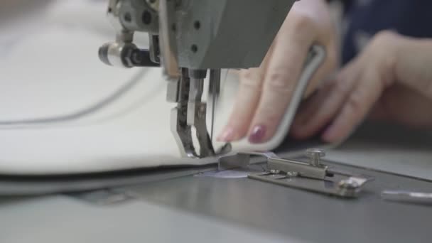 Man sews clothes on sewing machine, business fashion of modern seamstress, a needle and thread are sewn making seam on fabric patterns, a dressmaker at a production factory, equipment for needlework — Stock Video