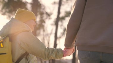 Sırt çantalı bir çocuk, güneş ışığında annesinin elini tutarak okula gider, annesi ile birlikte okul çantasıyla şehirde dolaşır, mutlu bir aile, kız okuldan sonra derse gider.