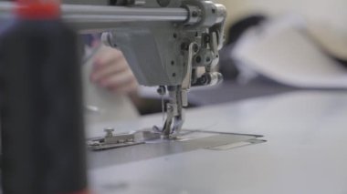 Adam dikiş makinesine kıyafet dikiyor, modern terzi modası, iğne ve iplik kumaş desenlerine dikiş dikiyor, bir üretim fabrikasında terzi, dikiş işi için ekipman dikiyor.