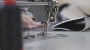 Adam dikiş makinesine kıyafet dikiyor, modern terzi modası, iğne ve iplik kumaş desenlerine dikiş dikiyor, bir üretim fabrikasında terzi, dikiş işi için ekipman dikiyor.