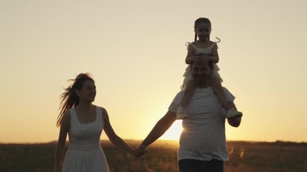 Vader moeder en kind lopen bij zonsondergang in de lucht, silhouet van gelukkig gezin, kleine jongen zit op papa schouders, familie reis, leuk leven ouders en dochter, spelen outdoor natuur superheld, weekend samen — Stockvideo