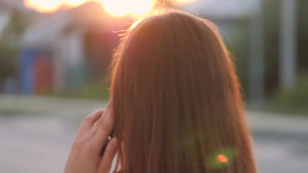 Ευτυχισμένο κορίτσι περπατώντας στους δρόμους της πόλης και μιλώντας στο smartphone στο φως του ήλιου, χαρούμενο φοιτητή πανεπιστημίου στο φως του ηλιοβασιλέματος, επιχειρηματική ιδέα, την αφή της τεχνολογίας του τηλεφώνου — Αρχείο Βίντεο