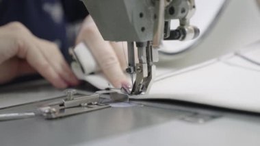 Adam dikiş makinesine kıyafet dikiyor, modern terzi modası, iğne ve iplik kumaş desenlerine dikiş dikiyor, bir üretim fabrikasında terzi, dikiş işi için ekipman dikiyor.