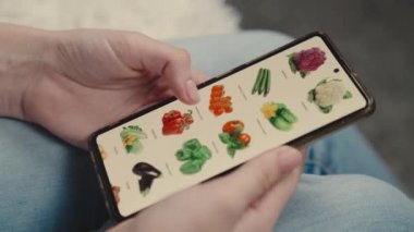 Kız eli sebze akıllı telefon, çevrimiçi sebze süpermarketi, çevrimiçi bir market, uzaktan alışveriş yapan bir iş, sepetten sipariş vermek, sağlıklı vejetaryen yiyecekler.