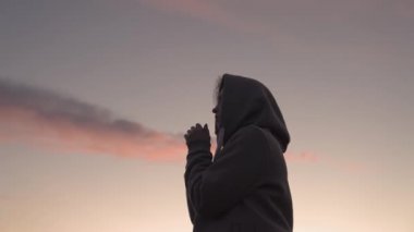 Pembe gökyüzü arka planında dua eden bir kız, iyiliğe inanır, yardım ister, rüya görür, motivasyon dışarıda ilham verir, kadın meditasyon yapmayı düşünür, seyahat tutkusu kavramı, ilahi ışık