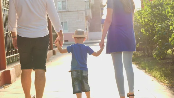 Anne ve babasının ellerini güneş ışınlarında tutan küçük bir çocuk, çocukla birlikte şehirde yürüyor, mutlu bir aile, anne, baba ve çocuk güneş ışığı altında, çocukluk hayali bebek hayatı — Stok fotoğraf