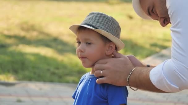 The father wipes the dirt off his son face, the little child gets smeared while walking on the playground, dad spend time with kid, keep his skin clean, be neat baby, father day, upbringing and care — Stock Video