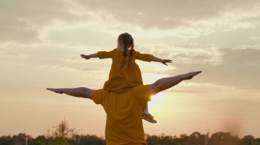 çocuk babasının omuzlarında oturur gün batımında uçmayı hayal eder, güneşin parıltısı pilot olmak ister, babasıyla birlikte oynamak ister, bebek doğada ebeveyniyle oynar, mutlu bir aile, seyahat