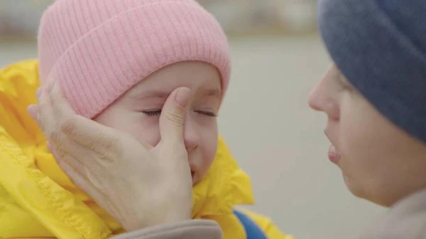 A criança está chorando, lágrimas amargas estão fluindo para baixo bochechas criança, a mãe acalma a filha caprichosa, menina está chateada e ruge, cuidados maternos e cuidados para o bebê, tremores nervosos das crianças — Fotografia de Stock