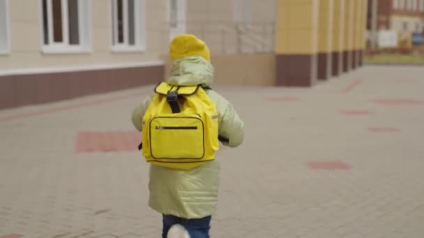 Μαθητής με σακίδιο τρέχει στο σχολείο στην αυλή του σχολείου, το παιδί σπεύσει σε ένα μάθημα για την πρόσκληση σε μια τάξη, παιδί με σχολική τσάντα στην πλάτη του, προσχολική εκπαίδευση, πρώτη τάξη με επιστροφή στο σπίτι μετά το τεστ — Αρχείο Βίντεο