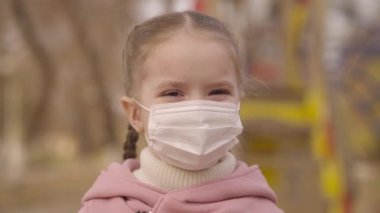 Küçük kız yüzüne tıbbi maske takıyor, çocuğu koronavirüs enfeksiyonundan koruyor, covid 19 salgını patlak veriyor, çocuk parkta yürüyor, bebek solunumuyla ilgileniyor, çocukluğunu maske modunda geçiriyor.