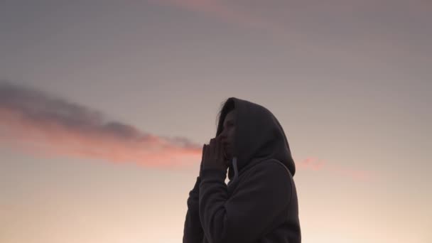 Een meisje bidt bij zonsondergang, een gelukkige man vraagt om vergeving uit de hemel, heeft berouw van kwade daden, leest gebed voor het slapen gaan, gelovige vrouw denkt aan goed en vriendelijk leven, kijkt omhoog met gevouwen handpalmen — Stockvideo