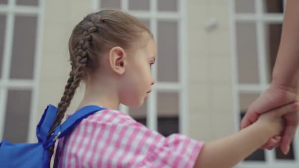 Kind haast zich naar school voor lessen, klein kind met school rugzak houdt zijn moeder met de hand, moeder leidt haar dochter school, kinderen schoolleven, gelukkig gezin, tas op de schouders van schoolmeisje — Stockvideo