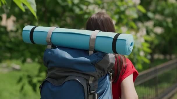 Ung tusenårig flicka reser med ryggsäck och turistmatta, ljus dag i livet, lycklig semester koncept, natursemester på turist väg, letar efter äventyr på semester, resenär koncept — Stockvideo