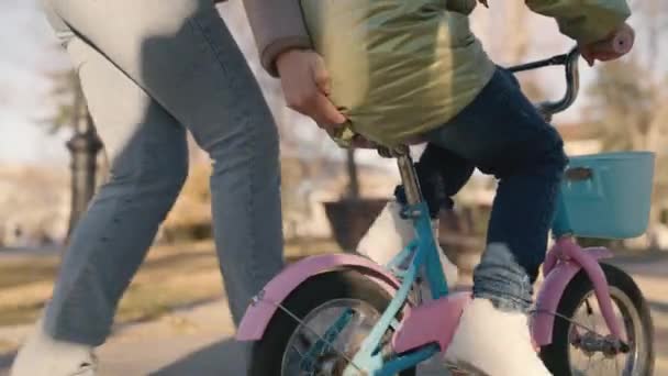 Μικρό παιδί μαθαίνει να οδηγεί δίτροχο ποδήλατο, παιδί παίζει με τη μητέρα του στο πάρκο της πόλης, ευτυχισμένη οικογένεια, μητέρα, διασκεδάστε με το μωρό στο δρόμο, γυρίστε πεντάλ και τροχούς γρήγορα, παιδικό όνειρο για να μάθουν βόλτα — Αρχείο Βίντεο