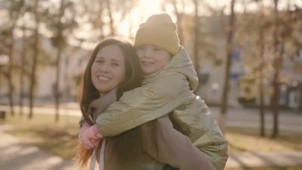 Little child hugs mom and laughs, mother circles her daughter in a city park in the glare of the sun, happy family, custody of a cheerful kid, baby smiles while spending the weekend with her mother at — Stock Video