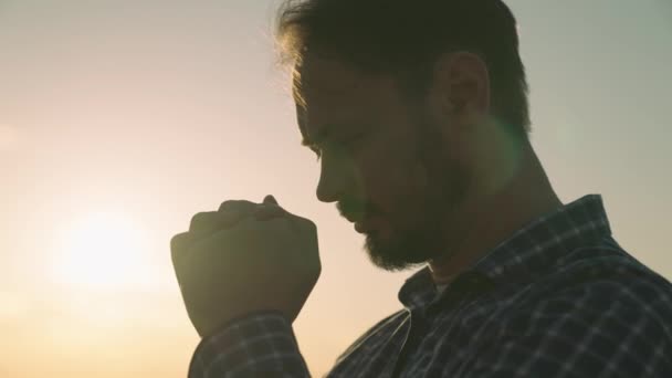 Hombre orando al atardecer, pidiendo ayuda y apoyo al cielo, hombre espiritual contemplando, el concepto de fe y esperanza, reflexiones en los rayos del sol, religión confiable — Vídeos de Stock