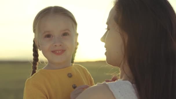 Pequeño niño abraza a la madre en los rayos del sol, familia feliz al atardecer, la mujer ama al niño, toma la maternidad un sentimiento agradable, niña hija con mamá en un viaje contra el cielo, custodia del bebé — Vídeo de stock