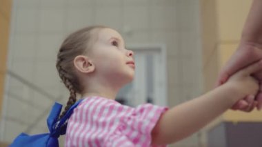 Çocuk ders almak için okula koşuyor, okul çantalı küçük çocuk annesini elleriyle tutuyor, anne kızını okula götürüyor, çocuklar için okul hayatı, mutlu aile, liseli kızların omuzlarında çanta.