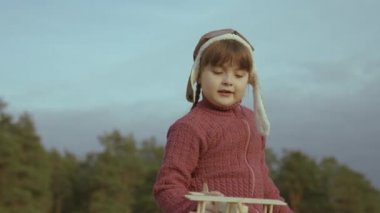 Kasklı küçük bir çocuk gökyüzüne karşı uçakla oynar, çocukluk hayali uçar, çocuk uçak pilotu olmak ister, hayal gücü, mutlu aile, neşeli bebek hayallerle uçar.