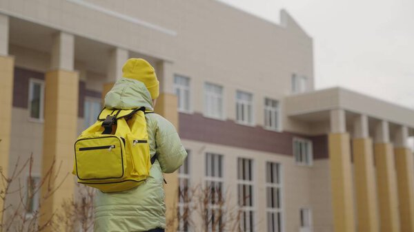 a small child with backpack goes to school, a kid with a school bag rushes to class, a happy girl, a first-grade student, schoolgirl of an educational institution, childrens time to learn new things.