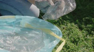 El poşete plastik bir şişe koyar, işlenebilen çöp, eko, çevreyi temiz, yeşil gezegeni güvenli, doğa orman ekosistemi, çevre koruma sorunu, hayır işleri