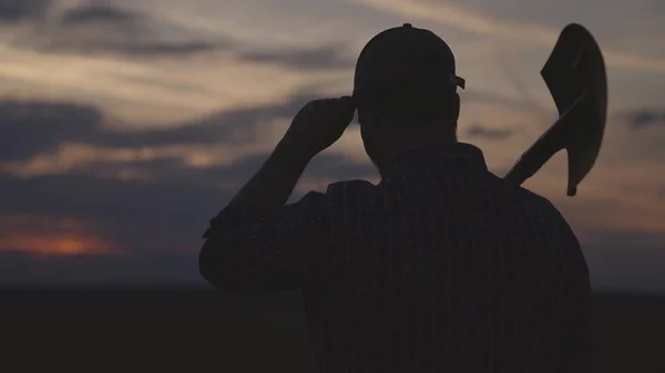 Silhouet van een boer met een schop, landbouw, gaan om land voor tuin te graven, voorbereiding voor het zaaien van gewassen, zaken op het platteland, tuinman gaat aan het werk om te graven bij zonsondergang, seizoen van de groenteoogst — Stockfoto