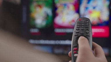 kız evdeki odada uzaktan kumandayı kontrol ediyor, hafta sonu dinleniyor, modern akıllı televizyonun uzaktan kumandası, kontrol TV ve film kanalları, kapalı ekran, bulanık ekran, akıllı sayfa kaydırma aygıtı