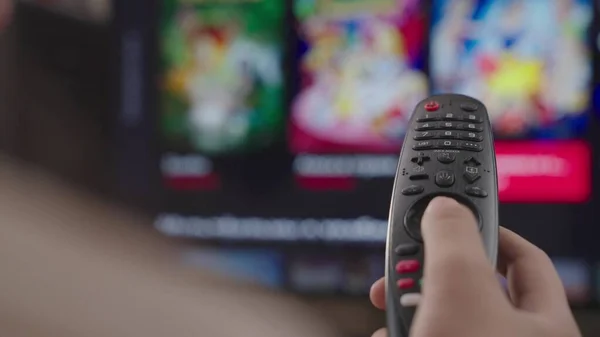 kız evdeki odada uzaktan kumandayı kontrol ediyor, hafta sonu dinleniyor, modern akıllı televizyonun uzaktan kumandası, kontrol TV ve film kanalları, kapalı ekran, bulanık ekran, akıllı sayfa kaydırma aygıtı