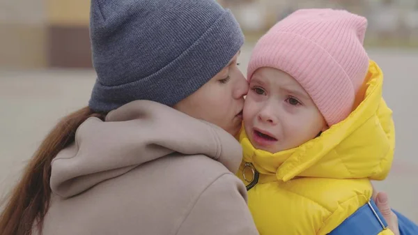 Mama uspokaja płaczące dziecko, mama wyciera łzy z twarzy i przytula dziecko z plecakiem, edukacyjnym programem szkolnym, martwi się o lekcje i stopnie, dziecko w ramionach rodzica Obrazy Stockowe bez tantiem