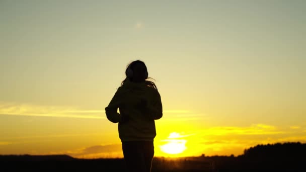 Silueta de una chica corriendo al atardecer, el amor deportes en movimiento corporal activo, entrenamiento cardiovascular al aire libre en la mañana del amanecer, lograr el éxito y ser persona sana, problema de celulitis y plenitud de piernas. — Vídeo de stock