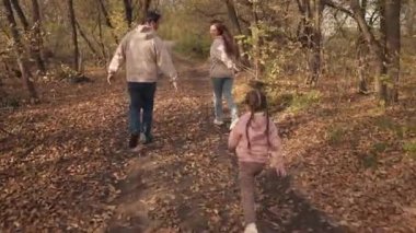 Annesi ve babasıyla sonbahar ormanlarında koşan küçük bir kız, mutlu bir aile, güler yüzlü bir aile, kızlarına sarılan, doğada bir gün dinlenen, anne ve babasıyla çocuk yürüyüşleri yapan.
