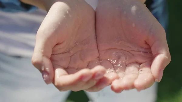 Manter a água limpa nas palmas das mãos, eco, refrescar-se em um dia quente de verão, manter as mãos limpas e saudáveis, o ambiente, gotas e salpicos de água molhada — Fotografia de Stock