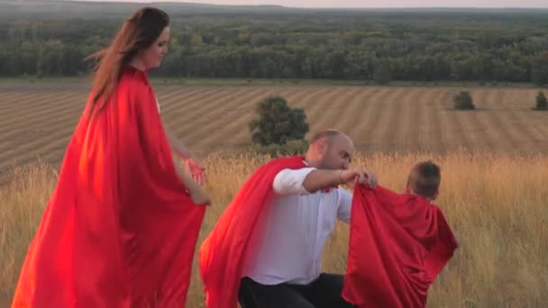 Criança pequena com mãe e pai jogando super-heróis vestidos com capas vermelhas, família feliz, traje salvador corajoso, heróis de sonho de infância fantásticos, vencedor menino destemido, diversão para jogar o jogo — Vídeo de Stock