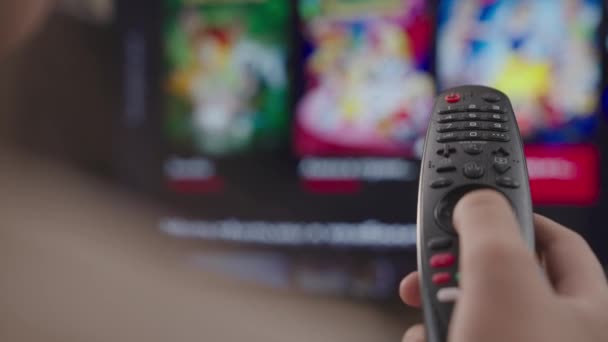 Ragazza controlla il telecomando della TV in camera a casa, riposo nel fine settimana, telecomando di una moderna smart TV, controllo TV e canali cinematografici, primo piano, schermo sfocato, dispositivo di scorrimento pagina intelligente — Video Stock