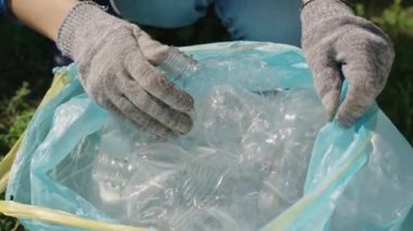El poşete plastik bir şişe koyar, işlenebilen çöp, eko, çevreyi temiz, yeşil gezegeni güvenli, doğa orman ekosistemi, çevre koruma sorunu, hayır işleri