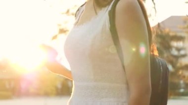 Genç bir kız elinde günbatımının parıltısıyla modern bir tablet tutuyor, internete giriyor, tabletin dokunduğu ekranda güneş ışınları parlıyor, modern teknoloji kavramı.