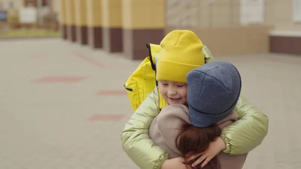 Dziewczynka uczennica z plecakiem biegnie przytulić matkę, dziecko raduje się z lekcji, szczęśliwa rodzina, torba szkolna za plecami wesoły śmiech dziecko, dziecko śpieszy jej matka jej ramiona, jogging szkolny dziedziniec — Zdjęcie stockowe
