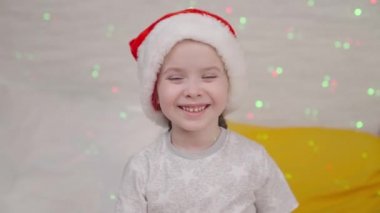Küçük çocuk Noel Baba şapkasıyla gülüyor, çocuk gülümsüyor Noel tatili, mutlu aile, bebek çelenk renkleri oynayarak eğleniyor, yeni yılda şenlik havası, mucize çocuk rüyasını bekliyor, hediye zamanı.