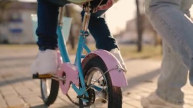 Küçük çocuk iki tekerlekli bisiklete biner, anne çocuğa bisiklet kullanmayı öğretir, bebek dümenleri dengede tutar, tekerlek ve bacağı yakın tutar, parkta yürür anne ve bebek, yol gezisi oyunu