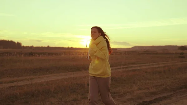 Een meisje joggen bij zonsondergang in de zon, man houdt van fitness, sport joggen marathon bij zonsondergang, jonge tieners motivatie voor training, een actieve levensstijl voor de gezondheid, cardio belasting van het lichaam — Stockfoto