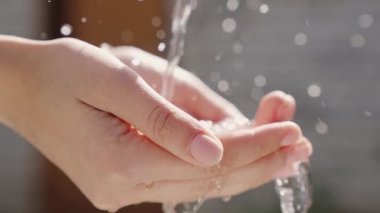 Ellere ıslak şeffaf temiz su akıntısı dökülür, temiz insan derisinin hijyenini gözlemler, parmakları nemlendirir ve yıkar, işten sonra temizler ve yıkar, kiri temizler, yakın plan temizler.