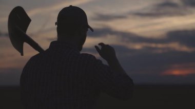 Kürek tarlası olan çiftçi silueti, tarım, bahçıvanlık bahar işleri, kırsal alanda yaz günbatımı, hasat zamanı, insan bahçıvanı çiftlikte arazi kazmaya gider, toprak çiftliği tarım işçisi.