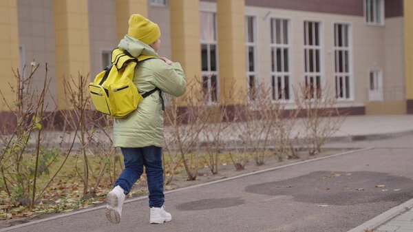 little child through schoolyard to school with a backpack, happy kid rushes runs to lesson in class, concept of school development of childhood, concept of elementary initial development of students